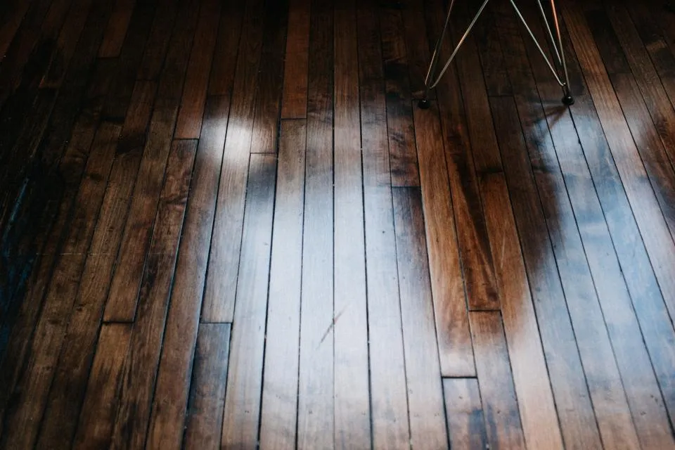 Worn hardwood floor with an uneven, patchy sheen